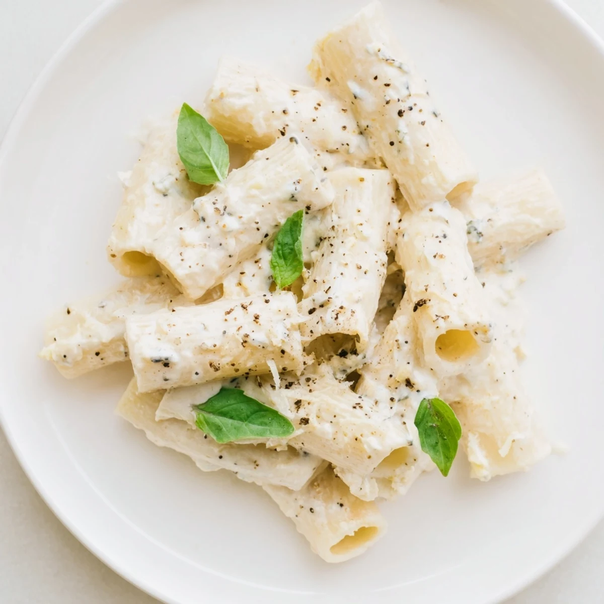 Creamy cottage cheese pasta, a comforting bowl, with swirls of silky, white sauce and fresh basil.