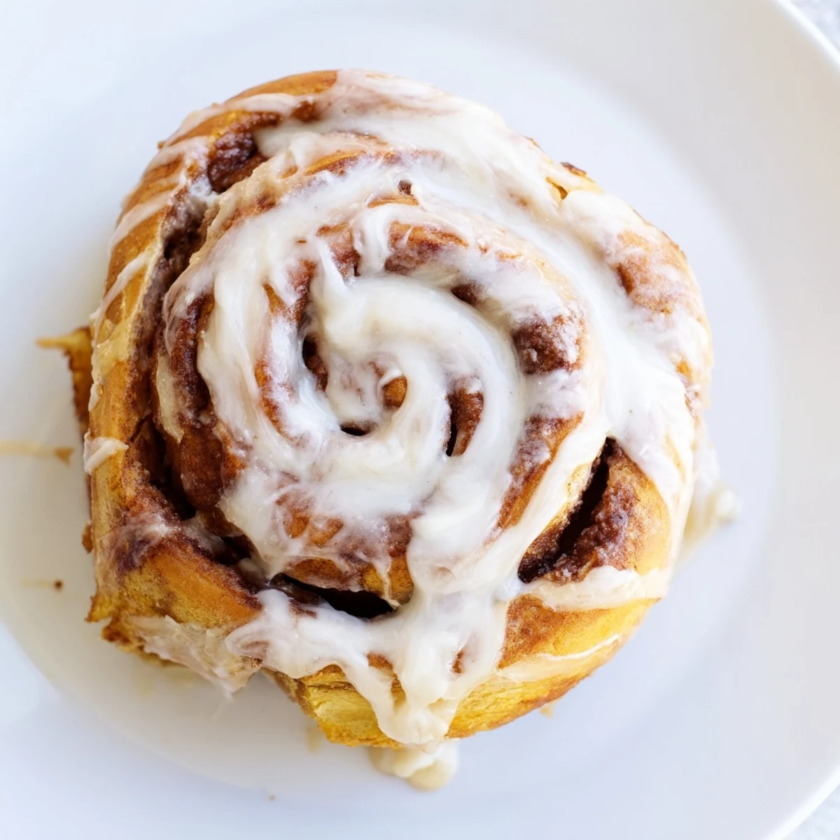 Freshly baked Pillow Soft Cinnamon Rolls with creamy glaze, served warm on a rustic wooden table.  