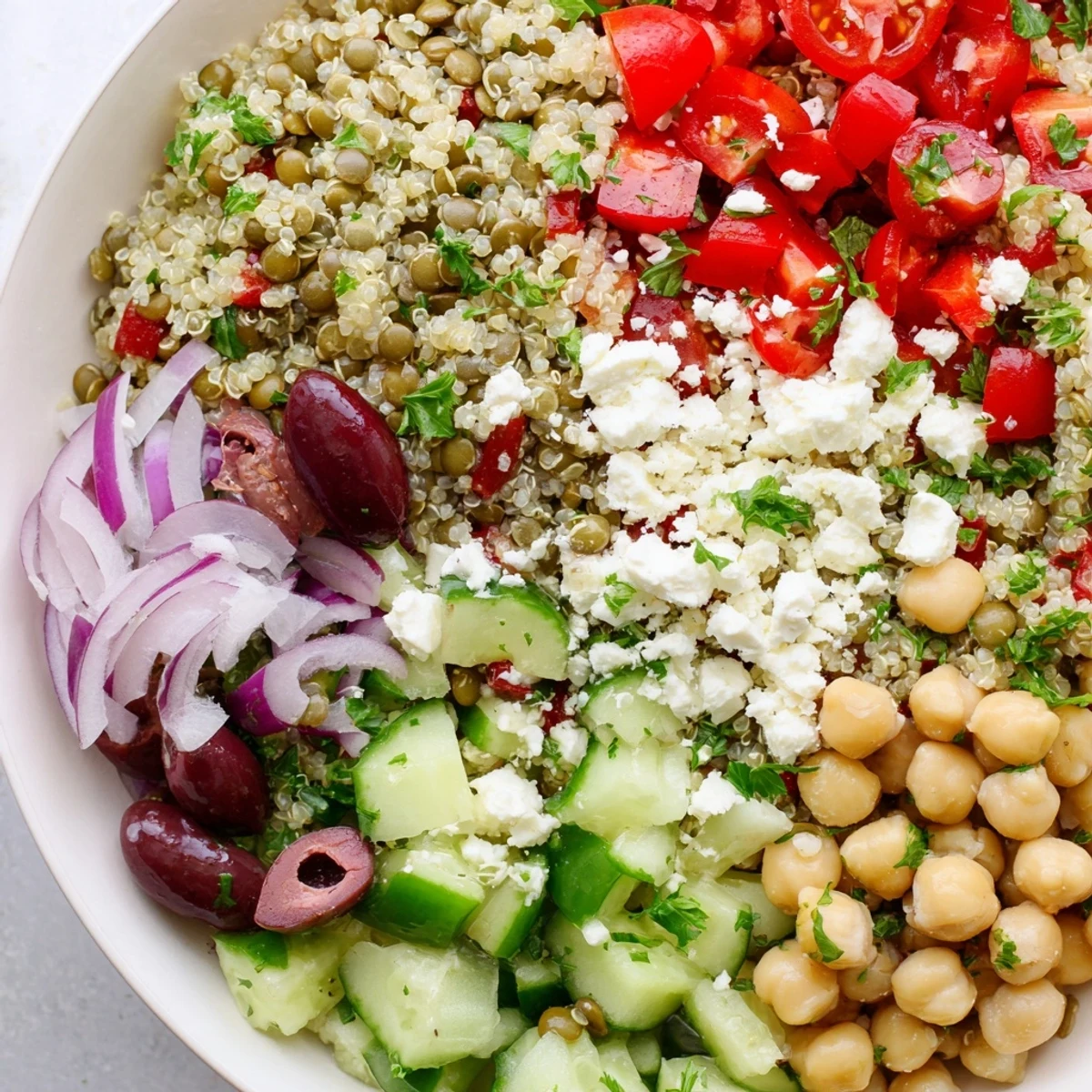 Served in a white bowl, the Greek Power Salad is topped with crumbled feta and Kalamata olives.