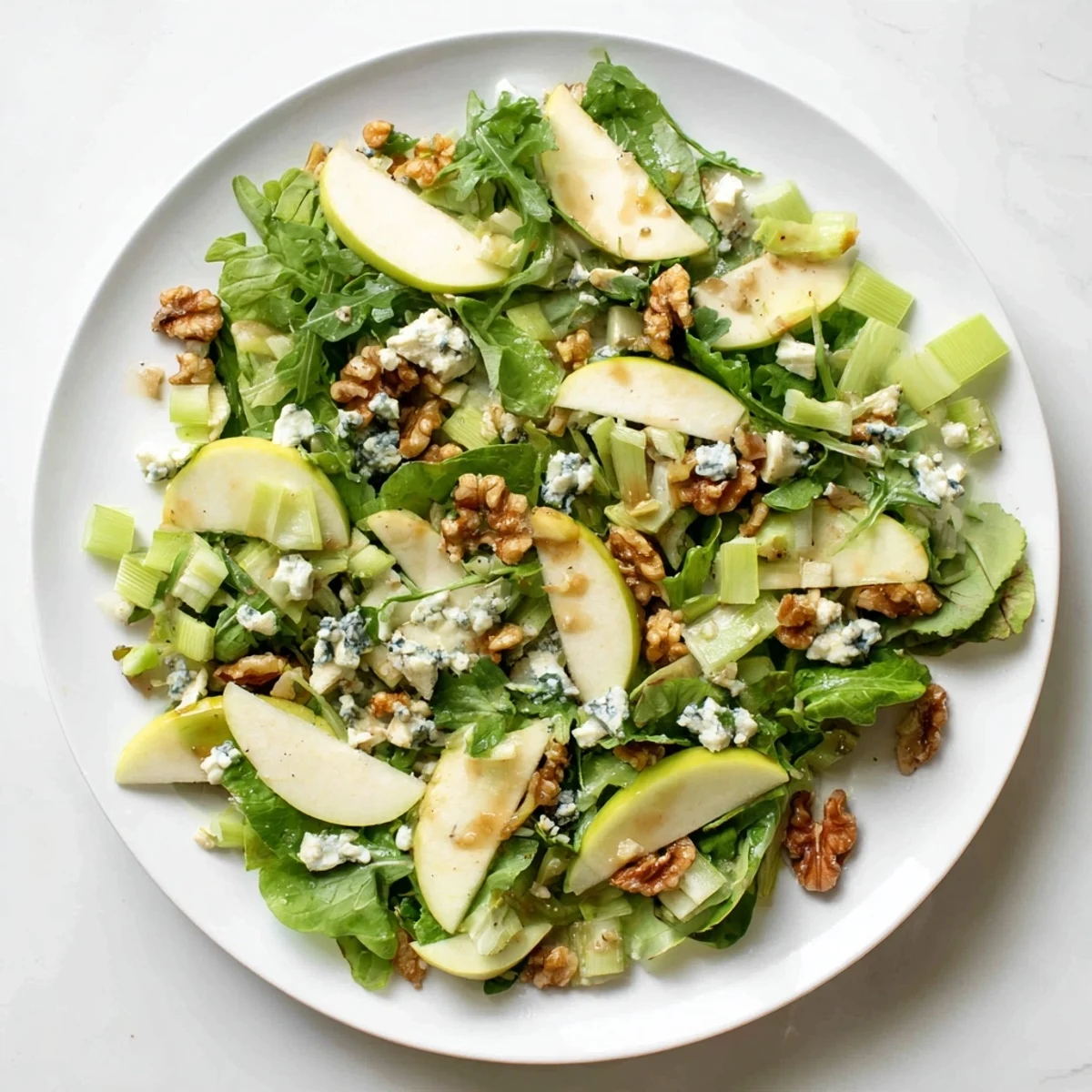 Freshly sliced crisp apples and crunchy walnuts tossed with mixed greens in a tangy vinaigrette, ready to serve.  