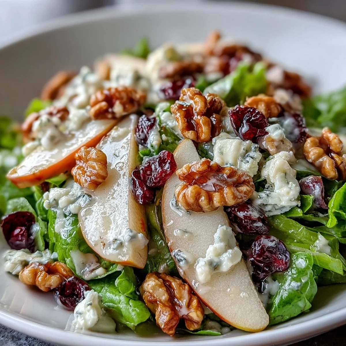 Pear Gorgonzola Salad features crisp mixed greens topped with juicy pear slices, crumbled Gorgonzola, and toasted walnuts.