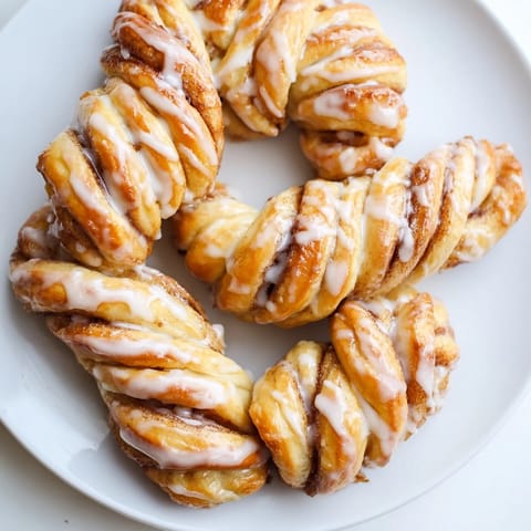 Flaky, golden Air-Fryer Cinnamon Roll Twists fresh from the air fryer, smelling warmly of cinnamon.