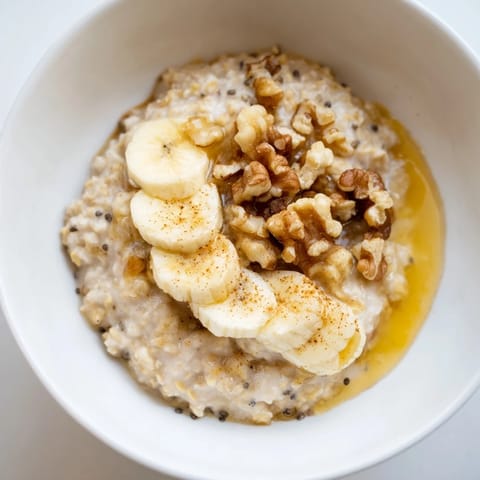 A close-up of a warm bowl of Microwave Banana Oats, sprinkled with cinnamon and nuts.