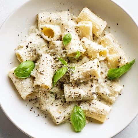 Enjoy a steaming plate of creamy cottage cheese pasta, perfectly coated, with grated Parmesan and pepper.