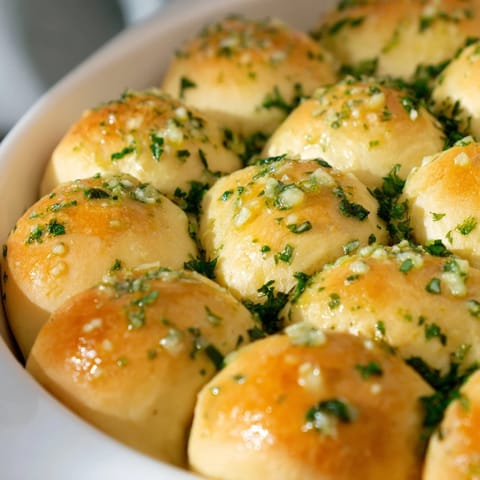 Freshly baked Garlic Butter Bread Pull-Apart rolls on a rustic wooden table, perfect for sharing at gatherings or serving with tomato soup.  