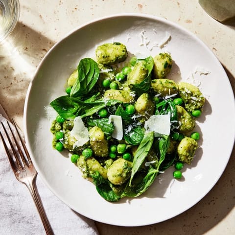 Pesto pea gnocchi skillet garnished with fresh basil and Parmesan, served warm as a hearty weeknight vegetarian dinner.