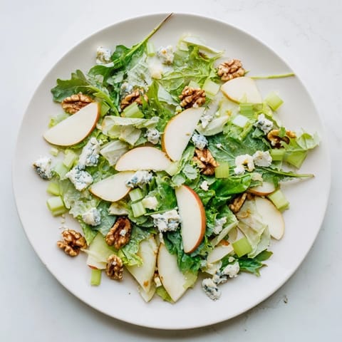 Apple and Walnut Salad plated with celery, crumbled blue cheese, and a drizzle of honey-Dijon dressing.  
