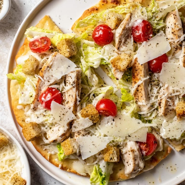 Close-up of a crispy, cheesy Chicken Caesar Flatbread, ready to eat with Caesar dressing drizzle.