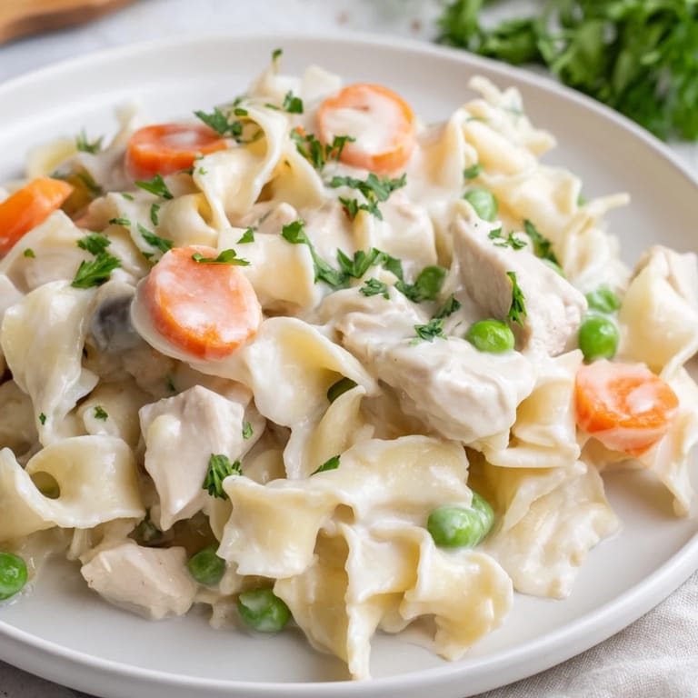 A close-up shot of rich and creamy chicken and egg noodles, garnished with fresh parsley.
