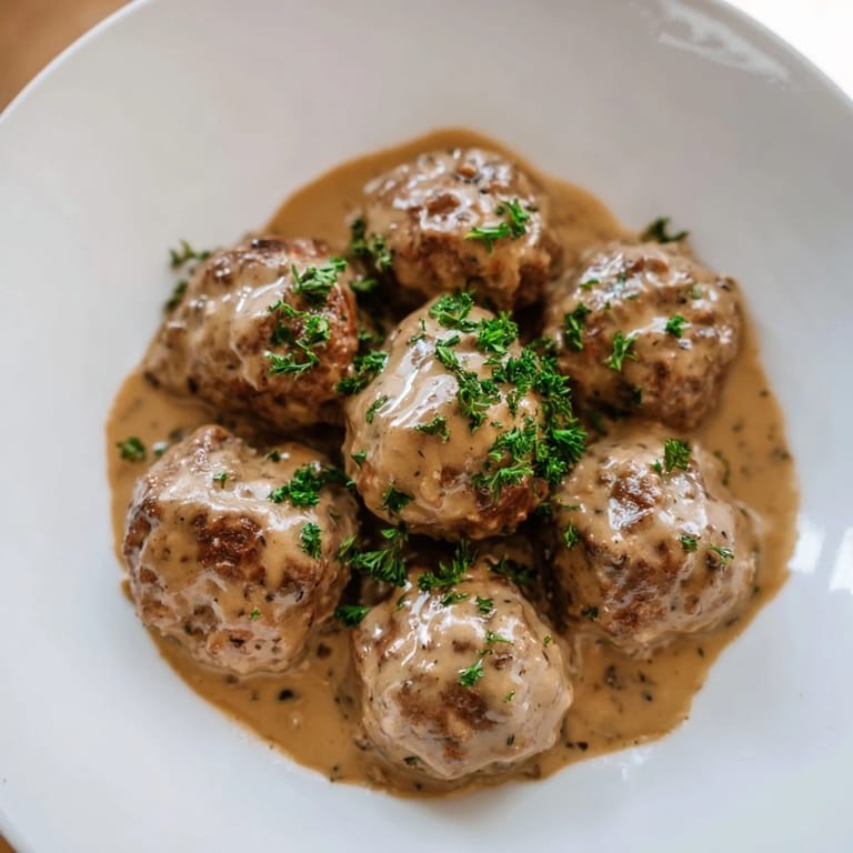 A close-up of tender Swedish Meatballs, deliciously presented with mashed potatoes and lingonberry jam.