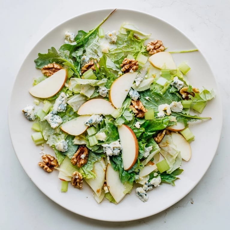 Apple and Walnut Salad plated with celery, crumbled blue cheese, and a drizzle of honey-Dijon dressing.  